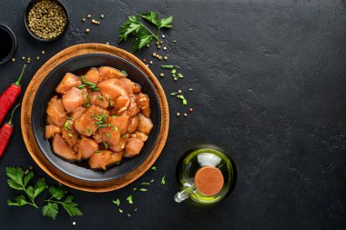 Teriyaki soya sosunda marine edilmiş çiğ tavuk eti, soğan ve biber siyah bir tabakta, taş, beton arka planda. Kopyalama alanı olan üst görünüm.