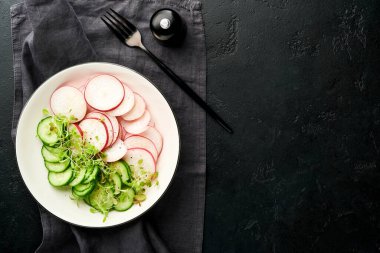 Kırmızı turplu taze salata, salatalık, sebzeler, gri taş zemin üzerinde beyaz tabakta mikroyeşil turplar. Yukarıdan bak. Vejetaryen ve sağlıklı beslenmeyi düşün..