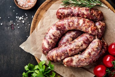 Çiğ sosis ya da parşömen kağıdına sosis ve yemek malzemesi. Taş tablo üzerinde kopyalama alanı olan üst görünüm.