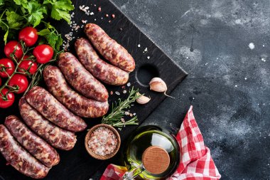 Çiğ sosis ya da baharat ve yemek pişirmek için malzemelerle kesilmiş sosis. Taş tablo üzerinde kopyalama alanı olan üst görünüm.