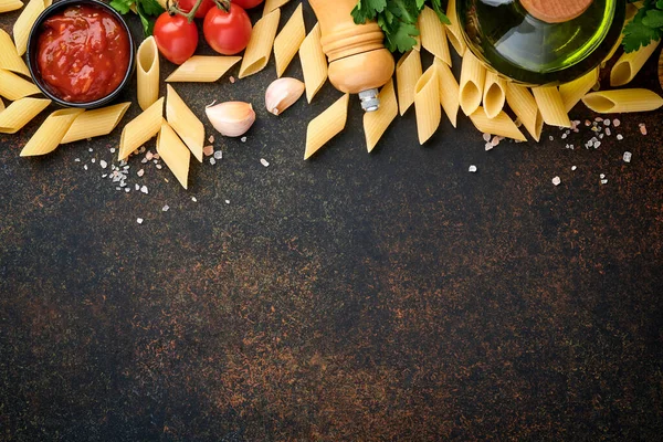 パスタの背景 パスタリガティ トマトケチャップソース オリーブオイル スパイス パセリ 暗いスレートテーブルの上に新鮮なトマト 料理の背景 コピースペース付きのトップビュー — ストック写真