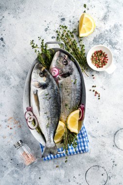 Çiğ dorado taze balığı ya da limon, kekik, sarımsak, kiraz, domates ve açık gri kayrak, taş ya da beton arkaplanda tuz yapımında kullanılan malzemelerle birlikte deniz çerezi. Kopyalama alanı olan üst görünüm.