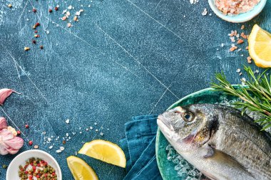 Çiğ dorado taze balığı ya da limon, kekik, sarımsak, vişneli domates ve buz üzerine buz, taş ya da beton arkaplan yapımında kullanılan malzemelerle birlikte deniz çamı. Kopyalama alanı olan üst görünüm.