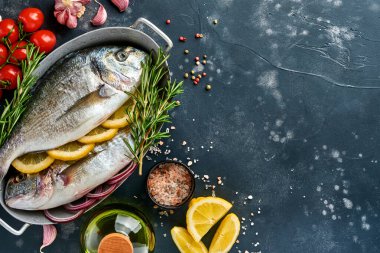 Çiğ dorado taze balığı ya da limon, kekik, sarımsak, kiraz, domates ve tuz yapımında kullanılan malzemelerle birlikte siyah kayalık, taş ya da beton zemin. Kopyalama alanı olan üst görünüm.