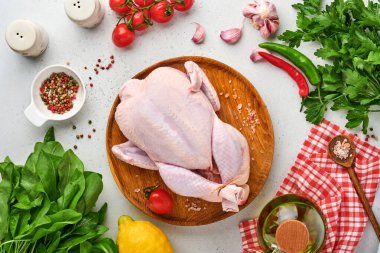 Biber, limon, kekik, sarımsak, kirazlı domates, sorrel ve tuz yapımında kullanılan malzemelerle dolu çiğ tavuk açık gri kayrak, taş ya da beton zemin üzerinde. Kopyalama alanı olan üst görünüm