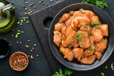 Teriyaki soya sosunda marine edilmiş çiğ tavuk eti, soğan ve biber siyah bir tabakta, taş, beton arka planda. Kopyalama alanı olan üst görünüm.