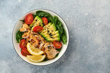 Taze yeşil salata ızgara tavuk fileto, ıspanak, domates, avokado, limon ve siyah susam tohumları ile beyaz tabakta zeytinyağı. Beslenme Diyet Konsepti. Üst görünüm.