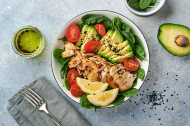 Taze yeşil salata ızgara tavuk fileto, ıspanak, domates, avokado, limon ve siyah susam tohumları ile beyaz tabakta zeytinyağı. Beslenme Diyet Konsepti. Üst görünüm.