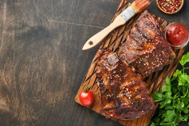 Eski bir ahşap kesme tahtasının üzerinde ızgara ve füme domuz pirzolası ve barbekü sosu. Lezzetli atıştırmalıklardan biraya. Resmi yaklaştır.