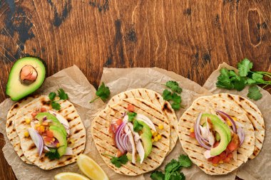 Izgara tavuk, avokado, mısır taneleri, domates, soğan, kişniş ve eski ahşap salsa masalı Meksika tacoları. Geleneksel Meksika ve Latin Amerika sokak yemekleri. Üst görünüm.