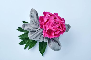 Bahar çevre dostu hediye. Gri tekstil ile sarılmış. Mavi üzerine pembe şakayık çiçekleri dekoru. Sürdürülebilir bir hediye. Geleneksel Japon Furoshiki tarzı. Yukarıdan görüntüle.