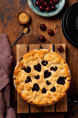 Tahta arka planda kalpleri olan ev yapımı vişneli turta. Sevgililer Günü pastası. Üst görünüm