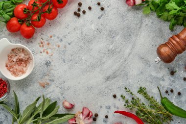 Yemek pişirme geçmişi. Taze safran, sarımsak, kişniş, fesleğen, kiraz domatesleri, biber ve zeytinyağı, baharat ve sebzeler açık gri kayrak masada. Gıda malzemeleri üst görünüm.