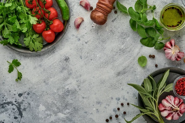 Food cooking background. Fresh saffron, garlic, cilantro, basil, cherry tomatoes, peppers and olive oil, spices herbs and vegetables at light grey slate table. Food ingredients top view.