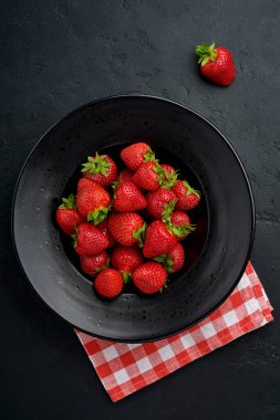 Siyah bir kasede taze çilekli bir hayat. Sulu çileklerin en iyi fotoğrafı. Sağlıklı beslenme konsepti. Kopyalama alanı olan üst görünüm.