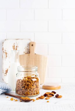 Parlak bir mutfak masasında sağlıklı bir kahvaltı hazırlamak için fındıklı ve kuru meyveli yulaf lapası. İskandinav beyaz tarzı. Seçici odak