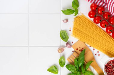 Spagetti, taze domates, otlar ve baharatlar. Beyaz arka planda izole edilmiş sağlıklı besin bileşenleri, üst görünüm. Model.