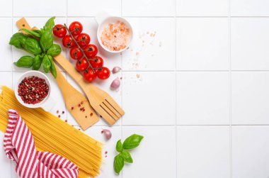 Spagetti, taze domates, otlar ve baharatlar. Beyaz arka planda izole edilmiş sağlıklı besin bileşenleri, üst görünüm. Model.