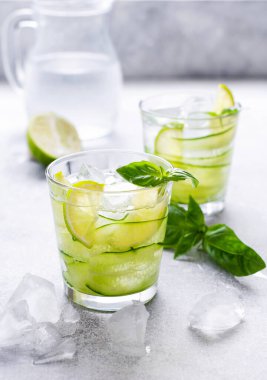 Limon, limon, salatalık ve eski beton arka planda buzlu fesleğenden yapılan ev yapımı limonata ferahlatıcı. Seçici odak