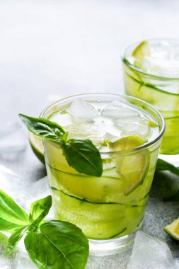 Limon, limon, salatalık ve eski beton arka planda buzlu fesleğenden yapılan ev yapımı limonata ferahlatıcı. Seçici odak