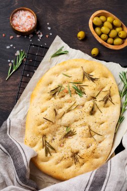 İtalyan geleneksel Focaccia ekmeği aromatik baharatlar ve eski ahşap masa arka planında biberiye. Üst görünüm