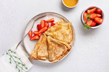 Krem peynirli krep ve güzel beyaz seramik tabakta taze çilek. Mesaj ya da tarif için boşluk. Üst görünüm.