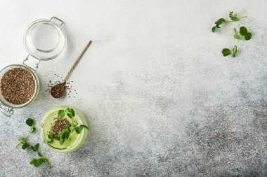 Yeşil smoothie, taze organik ıspanaklı bezelye mikroçim, muz, kivi, elma ve chia tohumu için açık gri beton zemin. Sağlıklı beslenme malzemeleri. Üst görünüm, alanı kopyala