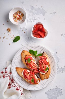 Çilekli sandviç, naneli yumuşak peynir ve açık gri taşlı arka planda seramik tabakta ceviz. Yaz ve sağlıklı diyet yemekleri, vejetaryen gıda konsepti. Üst görünüm.