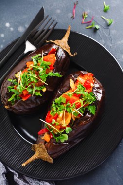 Farklı sebzeler, domates, biber, soğan ve maydanozla doldurulmuş patlıcan, siyah taş ya da beton masa arkaplanı. Üst görünüm