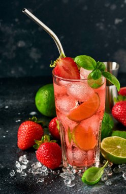 Bir bardak punç ve limonata, arınma suyu ya da kokteyl yapmak için taze malzemeler. Çilek, kireç, nane, fesleğen, buz küpü ve siyah taş ya da beton zemin üzerinde titretici. Seçici odak