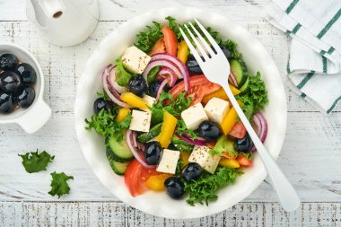 Geleneksel Yunan salatası, salatalık, domates, tatlı biber, marul, kırmızı soğan, beyaz tabakta zeytin yağlı beyaz peynir ve zeytin yağı. Sağlıklı yemek, en iyi manzara..