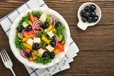 Geleneksel Yunan salatası, salatalık, domates, tatlı biber, marul, kırmızı soğan, beyaz tabakta zeytin yağlı beyaz peynir ve zeytin yağı. Sağlıklı yemek, en iyi manzara..