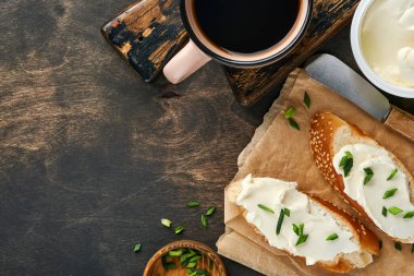 Yumuşak peynirli sandviç, yeşil soğanlı ve koyu ahşap arka planda ekmek. Ricotta sandviçi ve kahveyle basit bir kahvaltı. Metin için en üst görünüm kopyalama alanı.