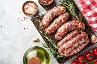 Çiğ sosis ya da baharat ve yemek pişirmek için malzemelerle kesilmiş sosis. Açık gri taş tablo üzerinde kopyalama alanı olan üst görünüm.