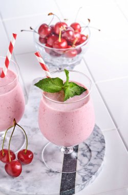 Taze kırmızı böğürtlenli pembe kiraz kokteylleri, chia tohumları, nane yeşili yapraklar, beyaz taş mutfak arka planı. Seçici odak.