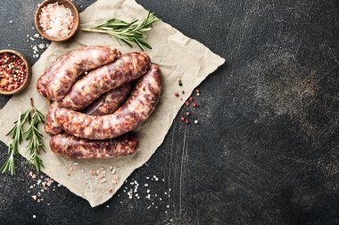 Çiğ sosis ya da sucuk ve koyu taş arka planda pişirmek için malzemeler. Kopyalama alanı olan üst görünüm.