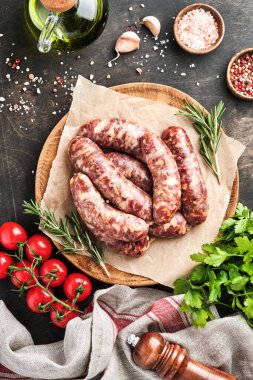 Çiğ sosis ya da sucuk ve koyu taş arka planda pişirmek için malzemeler. Kopyalama alanı olan üst görünüm.