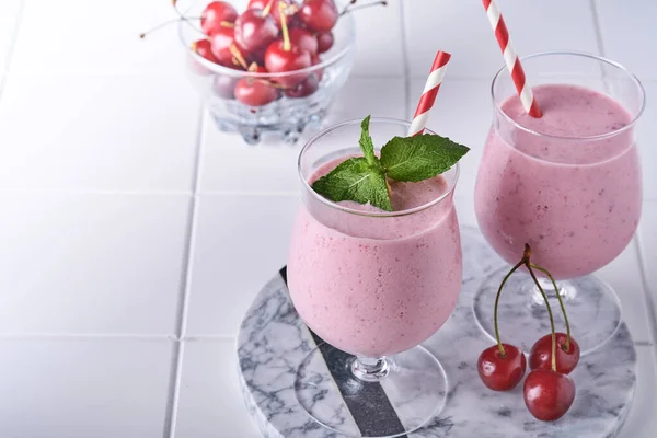 Smoothies de cereja rosa com baga vermelha fresca, sementes de chia, folhas verdes de hortelã, fundo de cozinha de pedra branca. Foco seletivo. — Fotografia de Stock