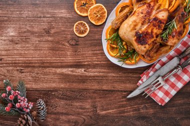 Biberiye ve portakallı fırında tavuk. Eski ahşap bir masada geleneksel Noel aile yemeği için yapılmış. Kopyalama alanı olan üst görünüm.