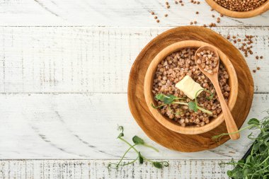 Eski beyaz ahşap arka planda maydanoz yaprağı ve tereyağlı karabuğday lapası. Ev yapımı yemek. Sağlıklı beslenme için glütensiz antik tahıl. Üst Manzara. Boşluğu kopyala.