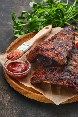 Eski bir ahşap kesme tahtasının üzerinde ızgara ve füme domuz pirzolası ve barbekü sosu. Lezzetli atıştırmalıklardan biraya. Resmi yaklaştır.