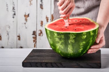 Kadın elleri, bir karpuzu ev ortamının arka planına karşı parçalara ayırdı. Seçici odak.