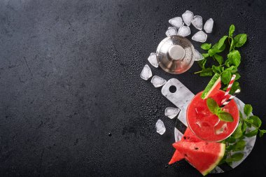 Naneli ve buzlu bir bardak karpuzlu Margarita kokteyli. Yaz, siyah masada bardaklarla içecekleri tazeler. Sağlıklı yaz yemekleri kavramı.