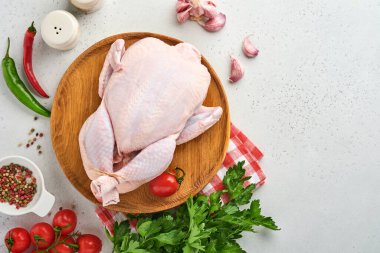İçinde gül biberi, limon, kekik, sarımsaklı domates ve tuz yapmak için malzemeler olan çiğ tavuk. Mutfakta açık gri kayrak taşı ya da beton zemin üzerinde. Kopyalama alanı olan üst görünüm