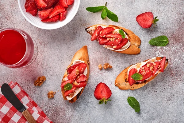 Çilekli sandviç, naneli yumuşak peynir ve açık gri taşlı arka planda seramik tabakta ceviz. Yaz ve sağlıklı diyet yemekleri, vejetaryen gıda konsepti. Üst görünüm.
