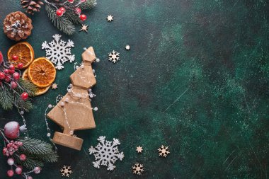 Noel ağacının çelengi, Noel baloları, hediye kutusu, tahta kar taneleri ve yeşil betondan arka planda yıldızlı Noel ağacı. Üst Manzara. Noel tebrik kartı..
