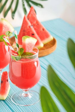 Naneli ve buzlu karpuz kokteyli. Yaz aylarında mavi ahşap masadaki bardaklarla içecekleri tazeliyorum. Sağlıklı yaz yemekleri kavramı.