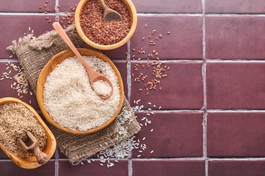 Pirinç, Yasemin, Kahverengi, Kırmızı, Kahverengi taş bir mutfak masasında, tahtadan bir kasede siyah. Glütensiz mısır gevreği. Kopyalama alanı olan üst görünüm.