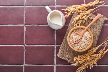 Tahta kasedeki yulaf gevrekleri ve kahverengi taştan mutfak masasında bir sürahi süt. Vejetaryen diyeti kavramı. Kopyalama alanı olan üst görünüm.