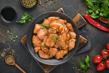 Teriyaki soya sosunda marine edilmiş çiğ tavuk eti, soğan ve biber siyah bir tabakta, taş, beton arka planda. Kopyalama alanı olan üst görünüm.